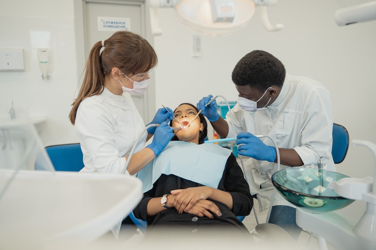 hero-img-02 Two dental professionals treat a patient in a modern clinic setting.